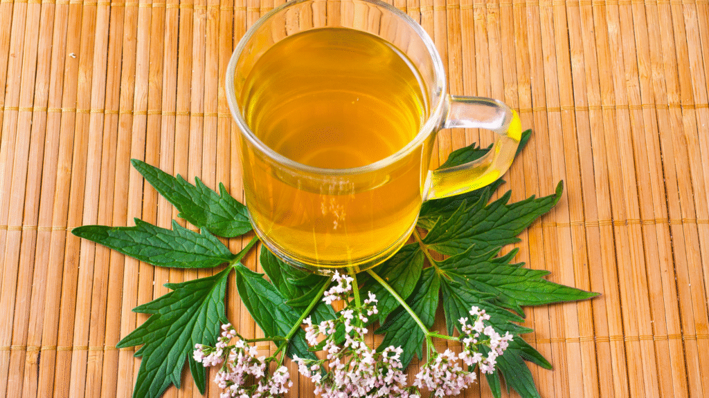 Taza de infusión de valeriana sobre hojas y flores frescas de la planta, utilizada como remedio natural para el insomnio.
