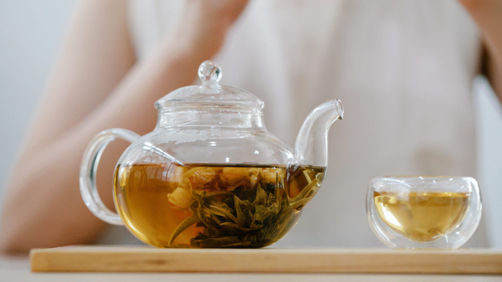 Tetera de vidrio con infusión de tila recién preparada y una taza servida, lista para tomar antes de dormir.